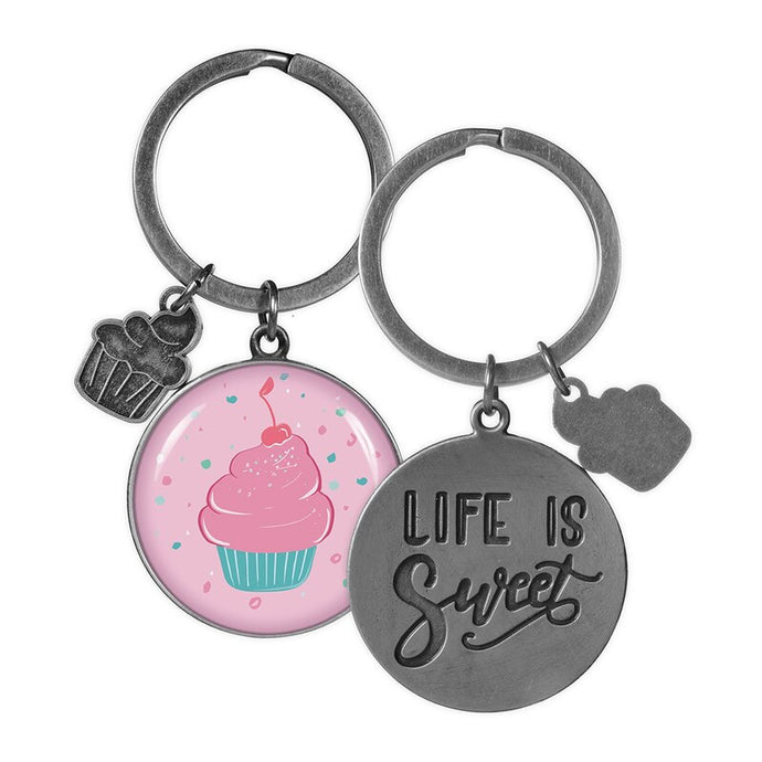 two key rings on a white background one has a picture of a cupcake the other shows the back of the keyring life is sweet.