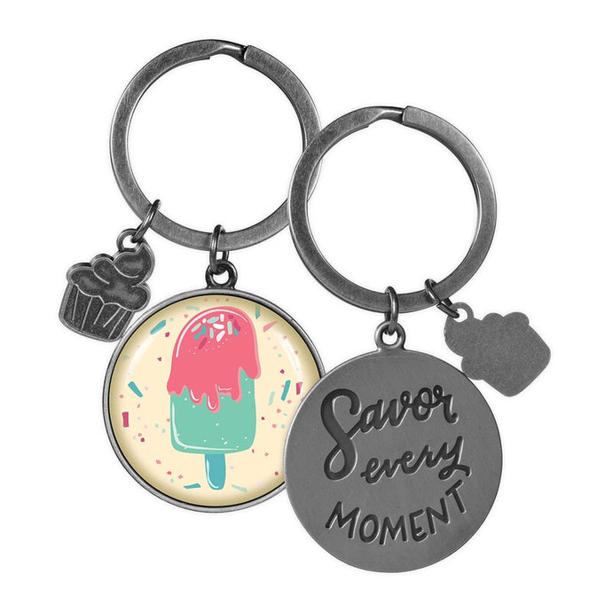 two key rings on a white background one has a picture of a lolly the other shows the back of the keyring savor every moment